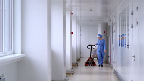 Warehouse-worker-moving-empty-pallet-lift-in-white-corridor.-Pallet-transport