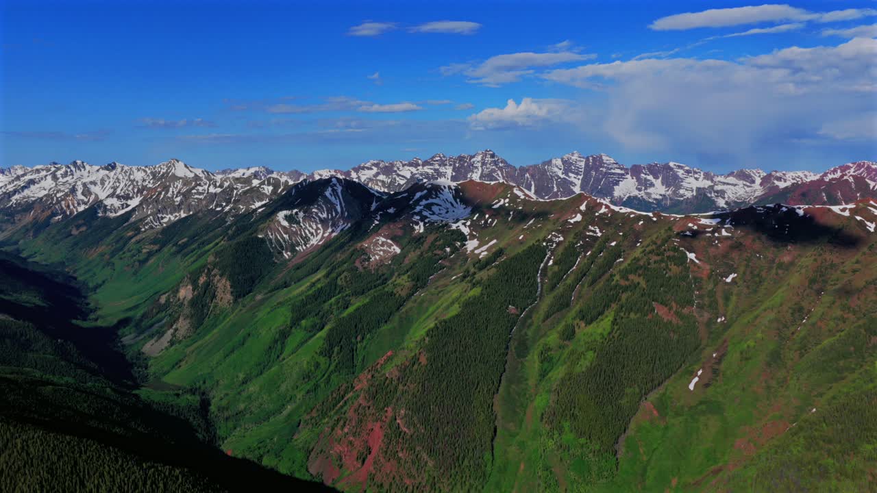 Summit Aspen Highlands bowl spring summer Maroon Bells Wilderness Pyramid Peak Elk Mountain Range aerial drone Colorado Snowmass Mountain Capitol Peak 14er sunny morning blue sky clouds circle left