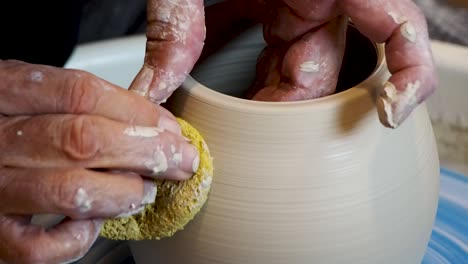 close up of the potter's hand shaping and molding clay on a turning wheel