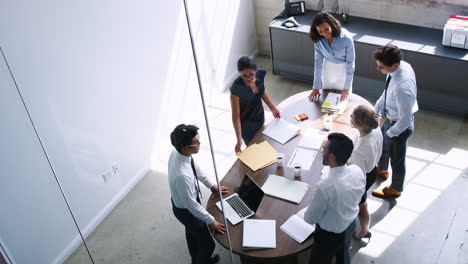 Business-colleagues-meet-standing-at-a-table,-elevated-view