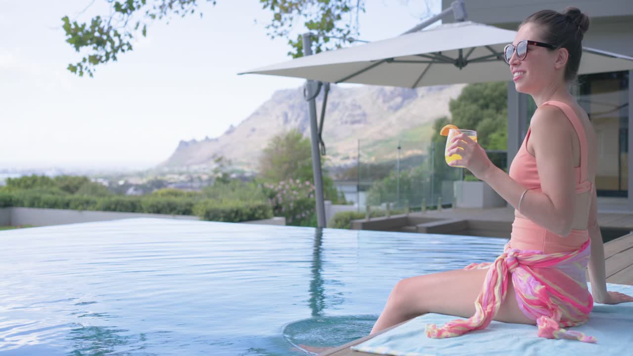 Woman seeing flipflops, sitting deck at infinity pool reaching cup dipping foot resting, copy space