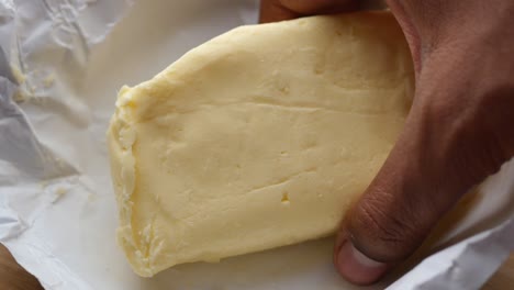 butter in a paper wrapper being held by a hand