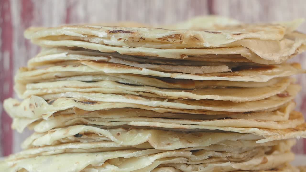 A close-up shot of a stack of golden brown flatbreads or crepes