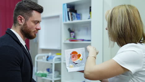 optical specialist and young man in medical center. doctor optometrist explaining to a male patient the eye care on an eye layout.