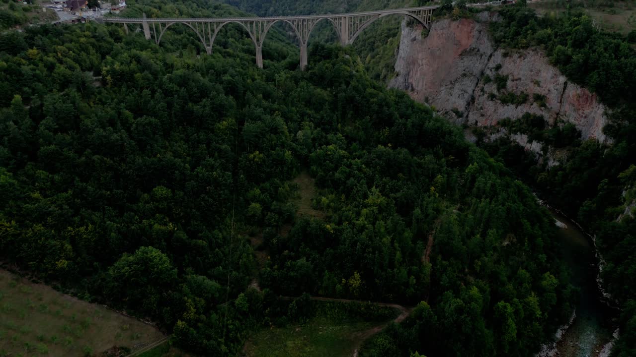 revelando la amplia vista aérea en el puente durdevica tara que muestra el paisaje bosque verde y montañas de montenegro cruzando el río tapa al atardecer en verano - aerial cinematográfica