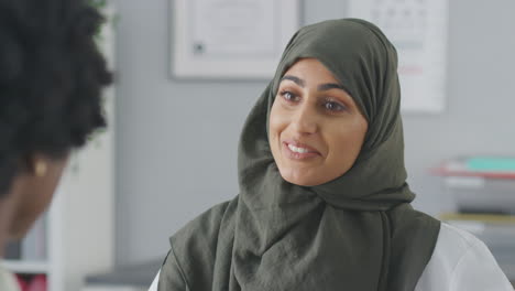 close up of female doctor or consultant wearing headscarf having meeting with female patient