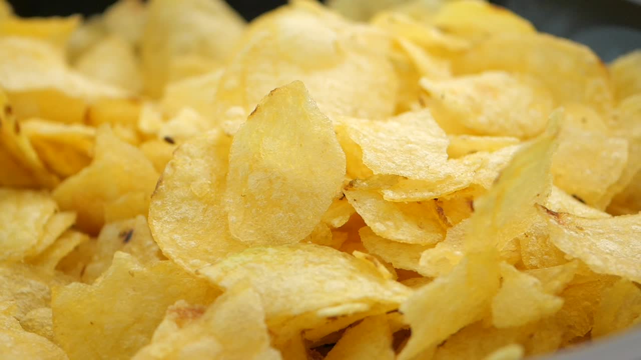 Close-up of Golden Potato Chips Falling into a Pile