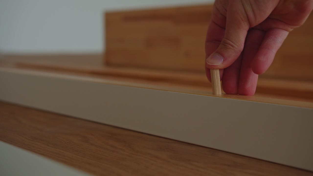 Inserting Wooden Dowels for Bed Frame Assembly in a Modern Bedroom Furniture House