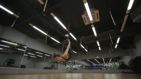 attractive woman doing aero yoga stretching exercises in hammocks at fitness studio. healthy lifestyle for female. workout gym