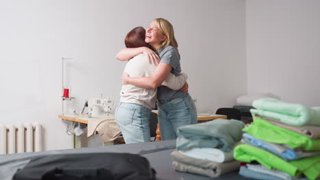 tailors hug beside neatly folded fabrics on cutting table, playful high five in sewing studio with sewing machines, denim jeans swishing, celebrating project success with teamwork energy