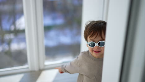 lovely little baby boy in sunglasses indoors. cute toddler child at home in the balcony.