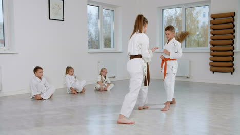 niños en kimono blanco en la clase de artes marciales
