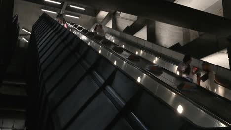 people riding a long escalator in a modern subway station