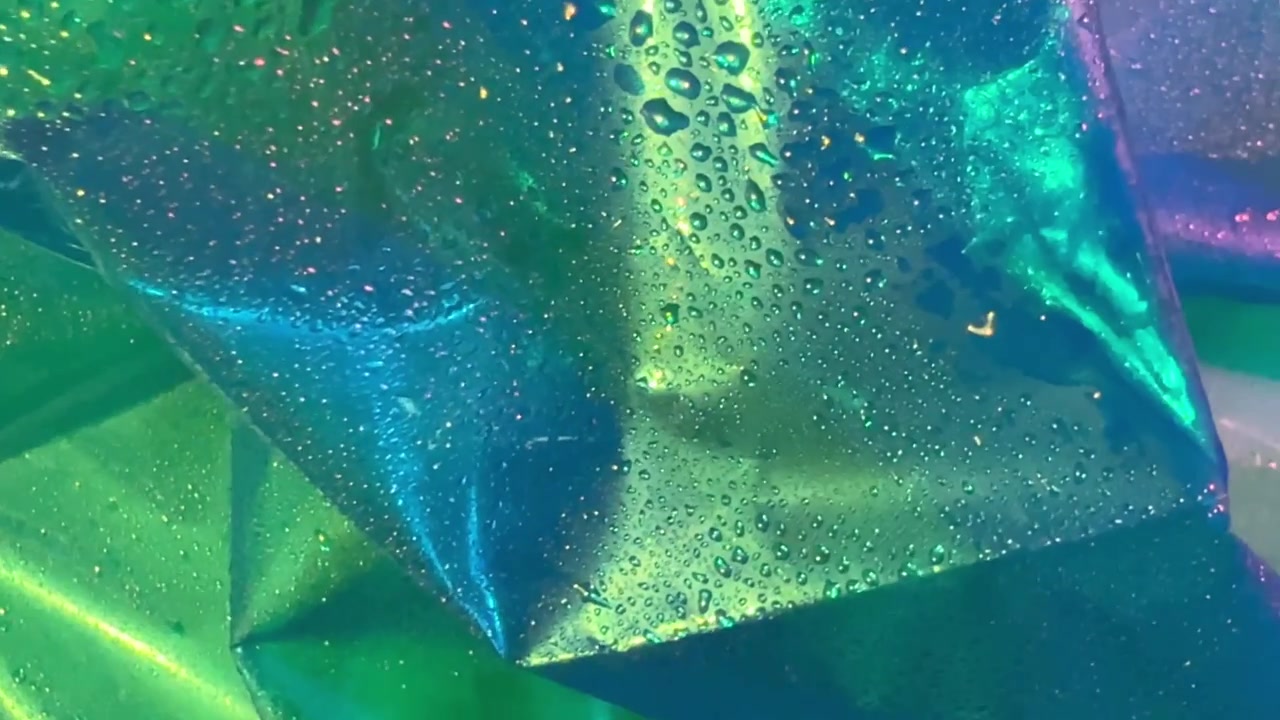 Sfondo astratto di pellicola di plastica verde iridescente con gocce d'acqua