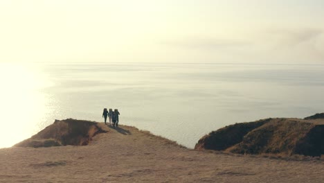 the four tourists with backpack walking in the mountains on the seascape