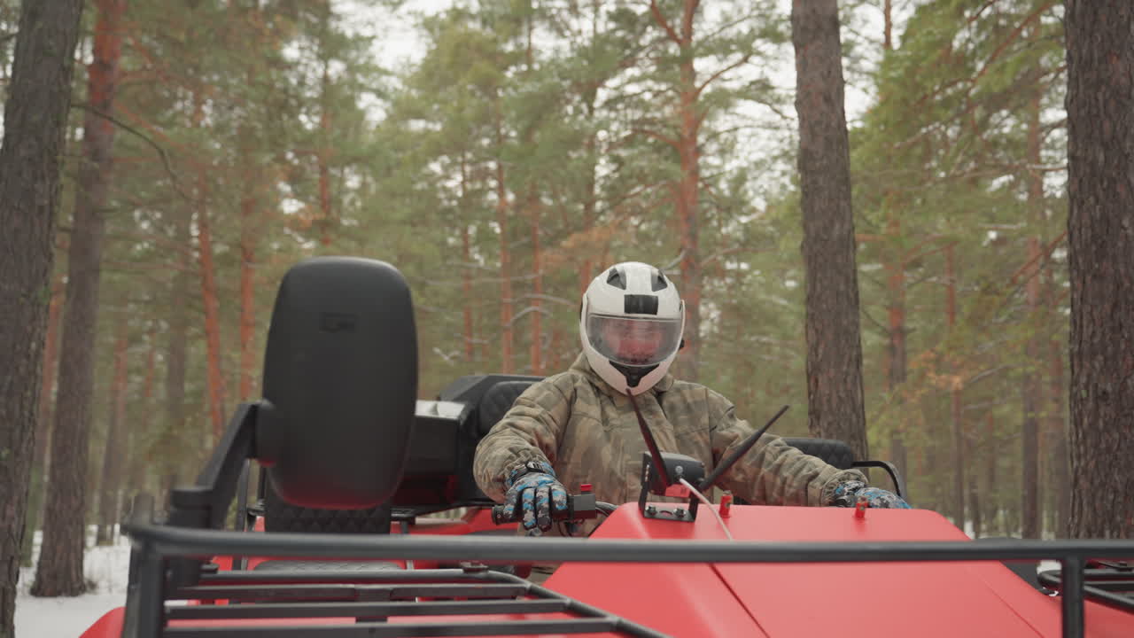Pilota di ATV in pineta innevata accelera tra gli alberi, il pilota con il casco aziona l'acceleratore su un quad rosso, rombo del motore e neve che vola, sterzata precisa e movimento dinamico, azione fuoristrada ad alta adrenalina.