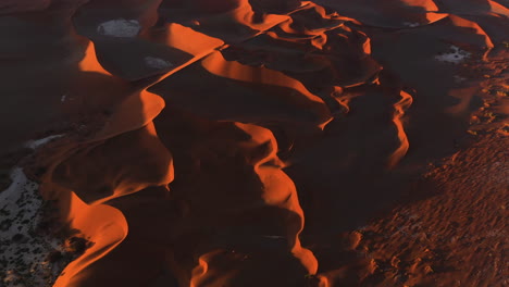 Scenic-view-of-a-natural-landscape-with-sand-dunes,-during-sunset---Aerial-shot