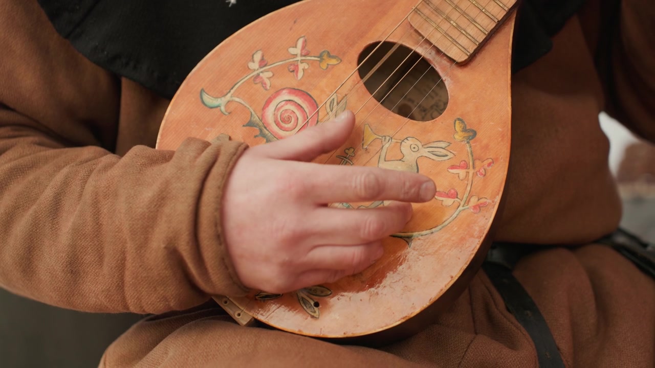 Kapalı bir ortamda ahşap bir müzik aletinin tellerini tıngırdatan veya çalan bir kişi, ellerin ve gövdenin yakın çekimi, kahverengi giysiler, teller, müzik dersleri, pratik, performans, doğal.