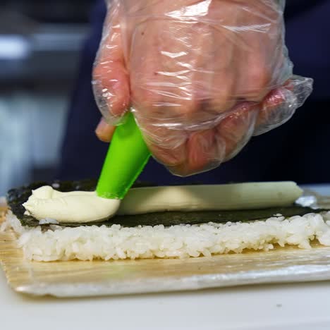 chef puts cream cheese on sushi. the process of sushi cooking, preparing. japanese cuisine concept. process of complex dish