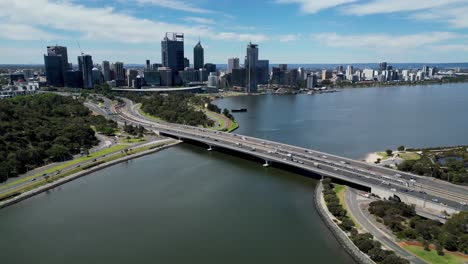 view by drone tracking towards perth, western australia, flying over narrows bridge on the swan river, train crossing the bridge between both lanes of traffic