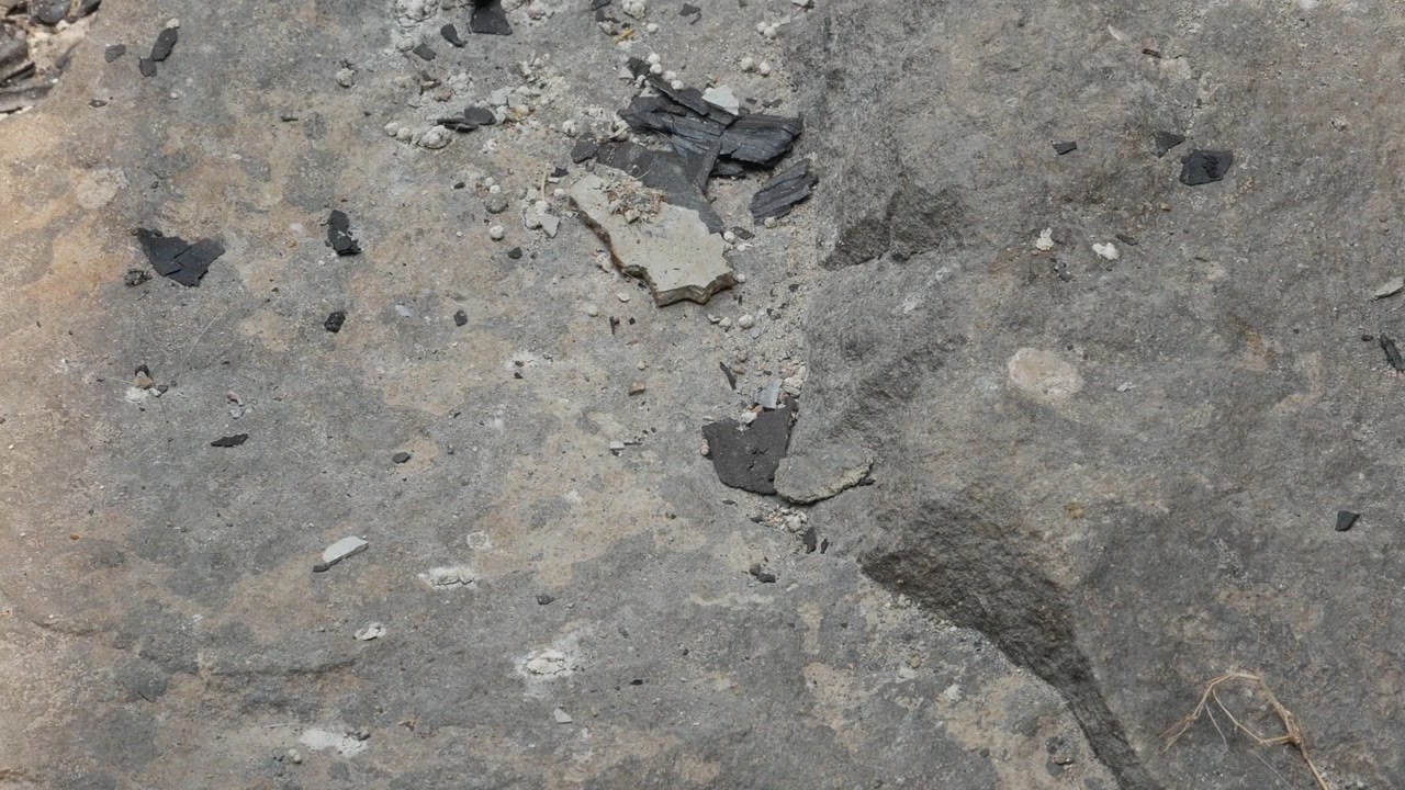 Forvitret betonoverflade med spredt affald som teksturbaggrund.