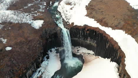 stunning landscape of svartifoss waterfall cascading on the river in south iceland.  - aerial drone ascending