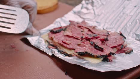 Pastrami-meat-and-cheese-on-aluminum-foil,-close-up