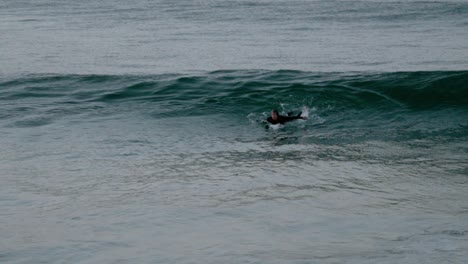 Kaukasischer-Mann-Im-Neoprenanzug-Auf-Surfbrettpaddeln,-Surft-Auf-Einer-Welle-Und-Fällt-Von-Seinem-Brett-Ins-Blaue-Wasser-Des-Ozeans