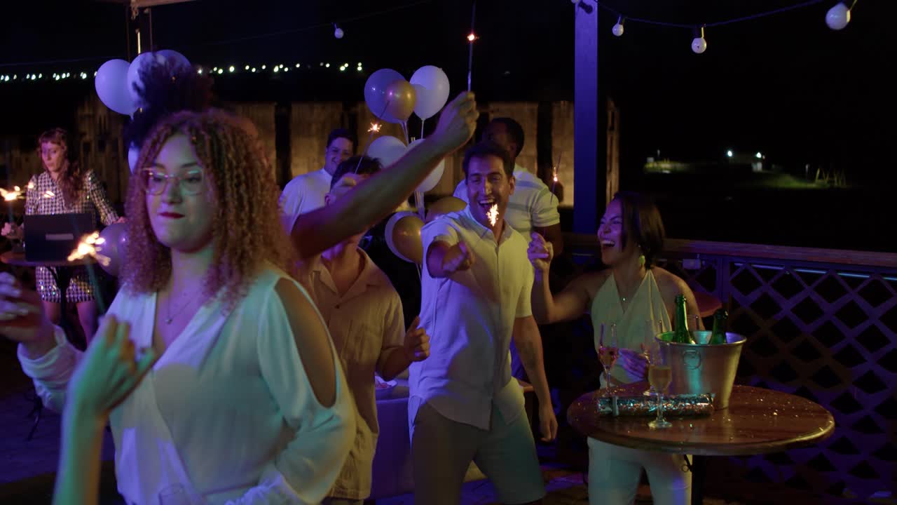 Friends Celebrating at a Night Party with Sparklers and Dancing