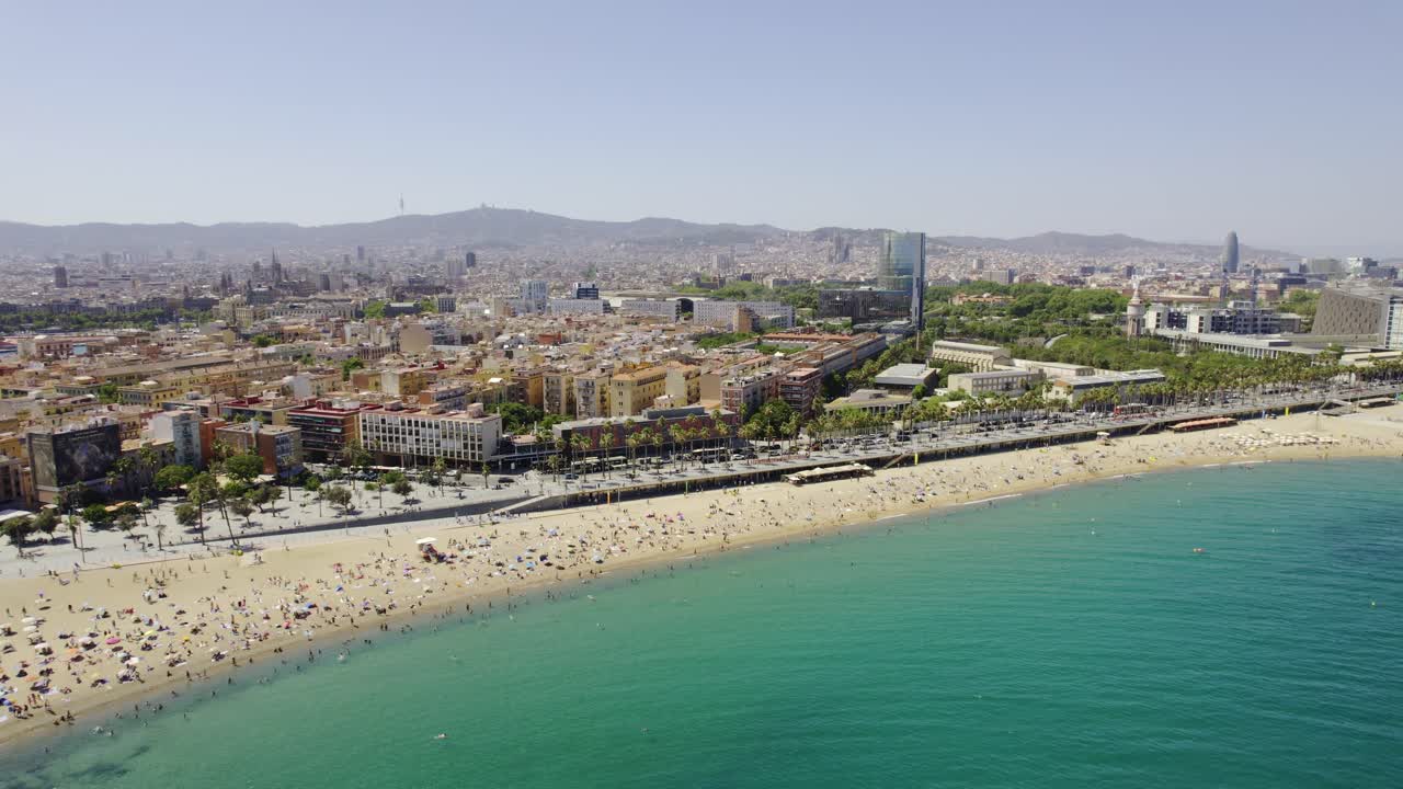 Vista aerea di una spiaggia affollata e dello skyline della città a Barcellona