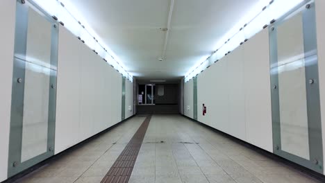 pov brightly illuminated empty tunnel underpass with modern architecture and tiled flooring.