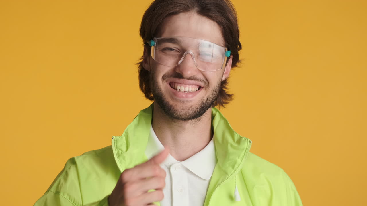 hombre caucásico frente a la cámara sobre un fondo amarillo.