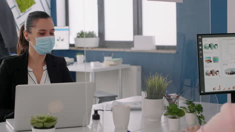 freelancers wearing protective face masks working on computer in business office