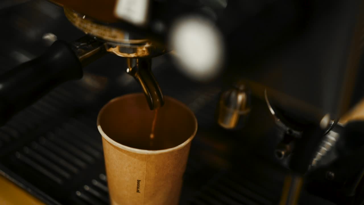 에스프레소 컵에 뜨거운 커피를 붓는 에스프레소 머신 주위를 미끄러지는 높은 각도의 클로즈업 샷