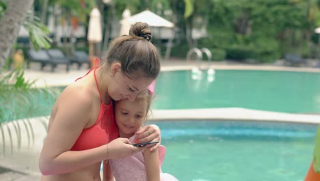 young-woman-in-swimsuit-hugs-child-with-purple-bow-on-head