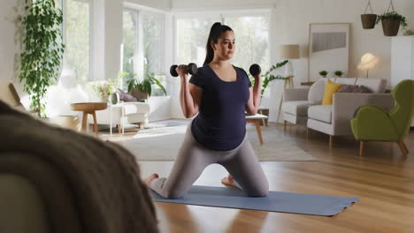 woman exercising with dumbbells on a yoga mat in her living room