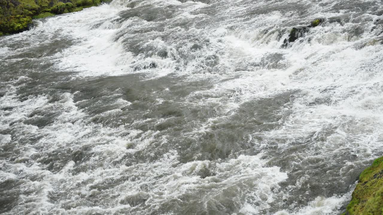 Slow panning shot of massive and wide rapid river flowing and gushing with white foam