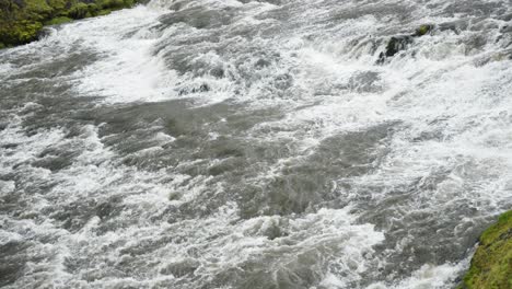 Slow-panning-shot-of-massive-and-wide-rapid-river-flowing-and-gushing-with-white-foam