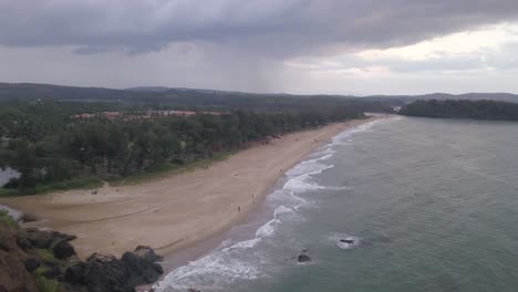 vista aérea de la playa de arena y la costa del océano en un día nublado en la playa de rajbagh, canacona, goa del sur, india - retirada aérea