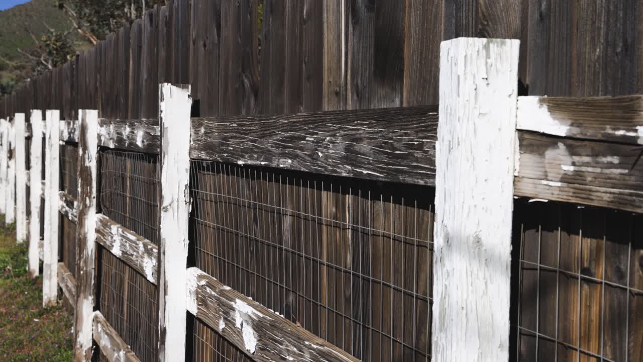 valla de madera adyacente a la valla de madera de alambre de gallinero pintada de blanco con pintura desconchada