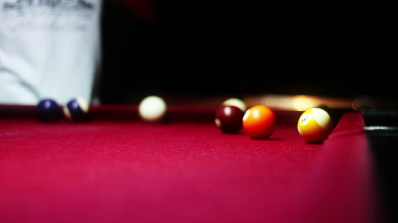 Gros plan de boules de billard se dispersant sur une table en feutre rouge.