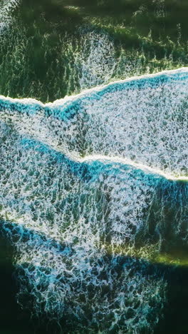 beautiful relaxing movement of foamy waves on the surface of ocean. descending drone footage over the deep green waters. vertical video