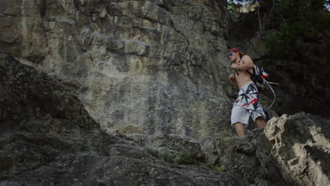 wide shot male hiker walking up on rocky trail with climbing backpack in rock mountain ridges, man hiking in spring summer