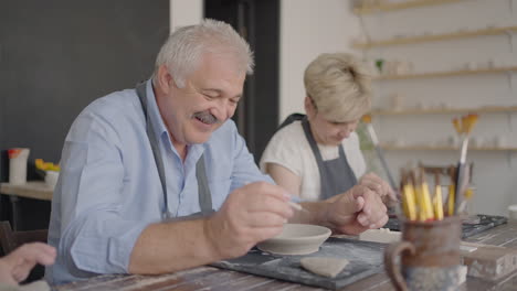 Three-elderly-people-work-on-a-potter's-wheel-in-slow-motion