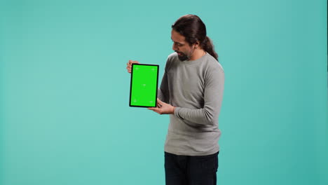 hombre alegre presentando video en la tableta de pantalla verde