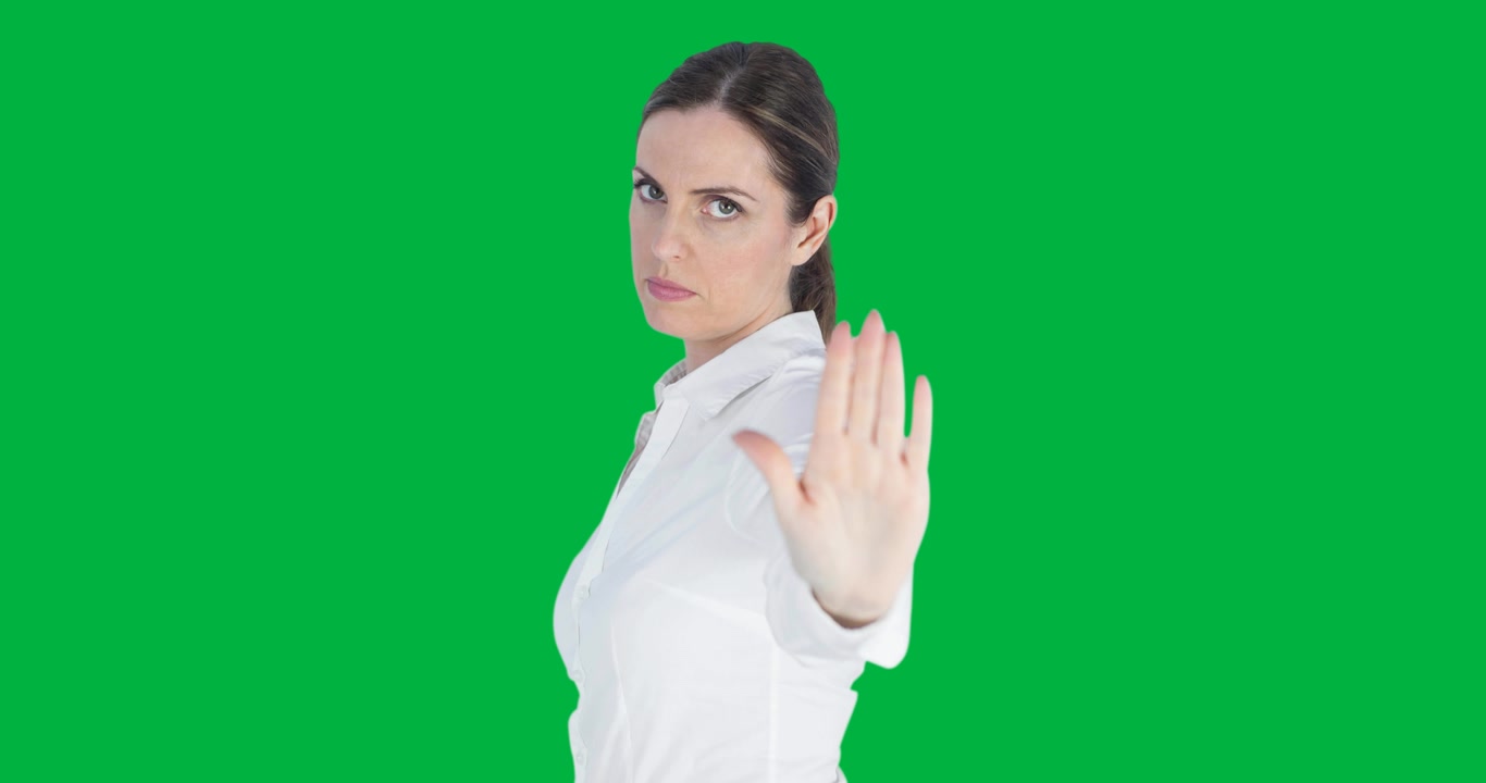 Ritratto di donna caucasica che fa il segno di stop con la mano su sfondo nero