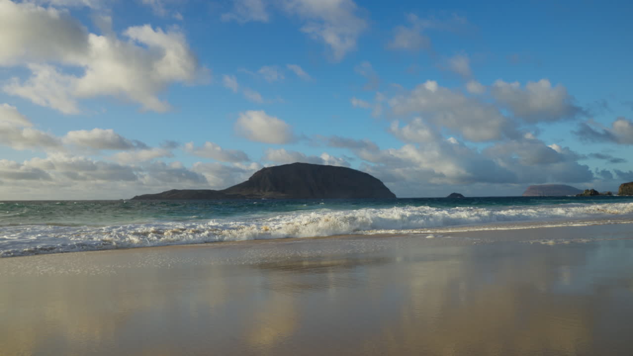 hermosa vista de una isla en lanzarote con algunas nubes en el cielo y olas rompiendo
