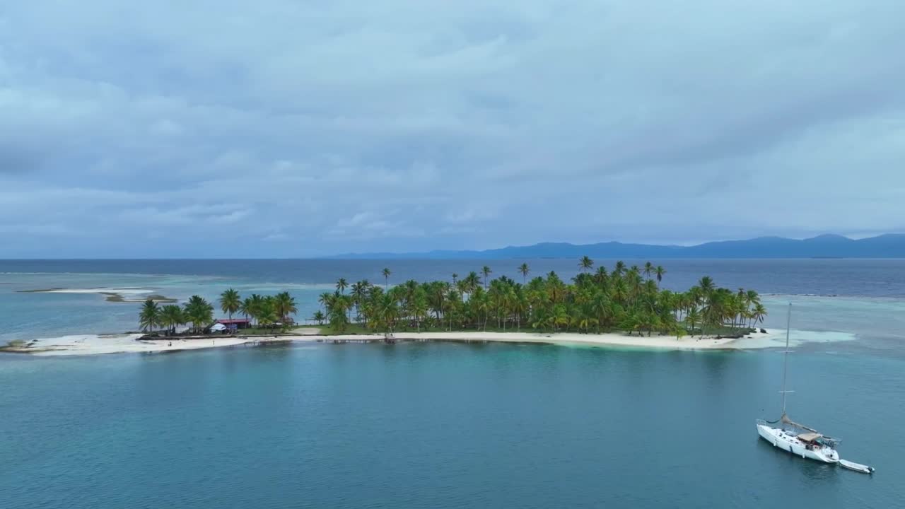 Drone past San Blas Island, Panama with sailboat cloudy sky. Drone dolly left to right Wide shot HD