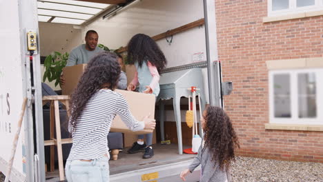 familia descargando muebles del camión de mudanzas en su nuevo hogar
