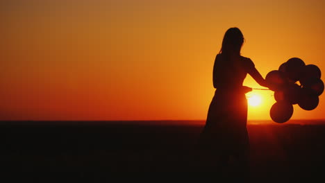 Silhouette-Einer-Frau,-Die-Sich-Bei-Sonnenuntergang-Achtlos-Mit-Luftballons-In-Der-Hand-Dreht